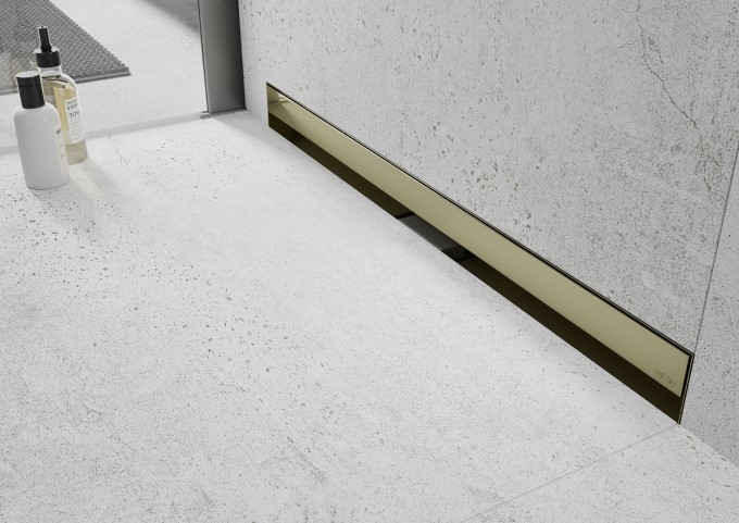 Caniveau de douche linéaire doré dans une salle de bains en béton